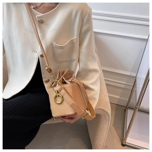 Detailed view of beige leather drawstring bucket bag with gold hexagonal metal buckle