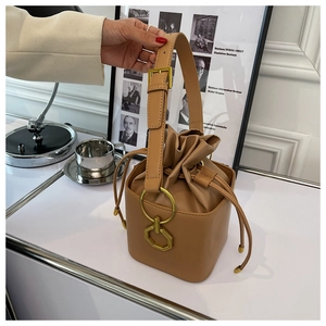 Macro detail of camel brown leather bucket bag showing drawstring and gold hardware