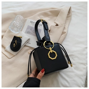 Detail of black leather bucket bag with gold metal hardware and detachable strap