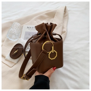 Detail of vintage brown leather bucket bag with gold geometric buckle and drawstring close