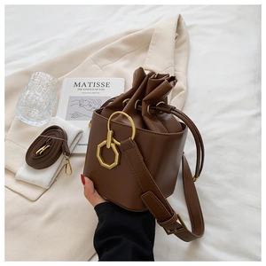 Detail view of a vintage dark brown bucket bag with gold hardware on a beige blazer