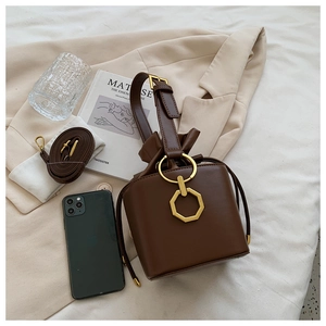 Detail of a vintage dark brown bucket bag with gold geometric buckle and leather strap