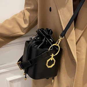 Vintage matte black drawstring bucket bag with gold hexagonal rings on model