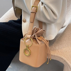Retro light brown drawstring bucket bag with gold hardware and square base shown on model