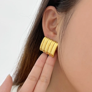 Detailed close-up of 18K gold-plated ribbed hoop earrings on model ear for women
