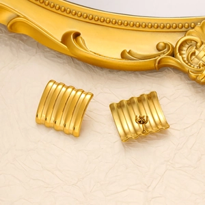 Detailed view of 18K gold wave textured rectangular earrings on a soft cream fabric