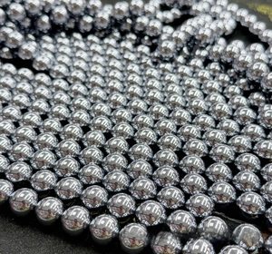 Detailed view of polished silver terahertz beads arranged in multiple rows on a dark background