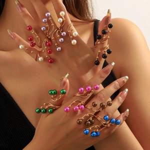Detailed view of colorful pearl beaded rings in gold settings worn by a model