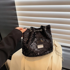 Detailed view of black sequin bucket bag featuring silver chain and metal nameplate