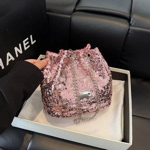 Detail of bright pink sequin bucket bag featuring silver chain strap and metal logo plate