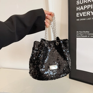 Detail of black sequined bucket bag with silver chain strap and metal logo plate