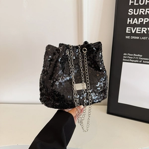 Detail of a sparkling black sequin bucket bag with silver metal chain and branding plate