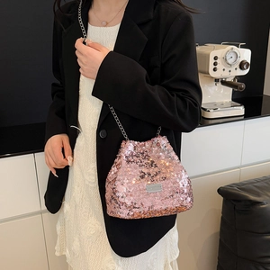 Close-up of light pink sequin bucket bag with silver chain strap and metal logo plate
