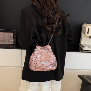 Detailed view of pink sequin bucket bag with silver chain strap worn by a model