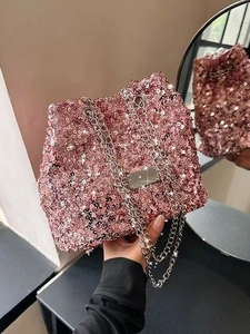 Chic pink sequin bucket bag with silver chain strap held by a model in indoor setting