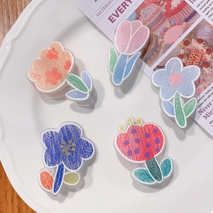 Close-up of five acrylic floral accessories with hand-drawn tulip and daisy patterns