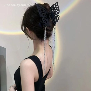 Detail of a matte black butterfly hair claw with silver tassel chains on an elegant updo