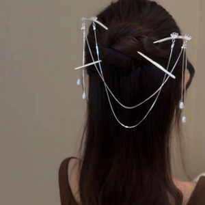 Silver hair sticks with flower ornaments and long tassels worn on a dark bun hairstyle