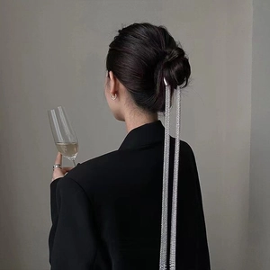 Close-up of elegant silver hair pin with long dangling tassels worn in a bun