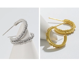 Detail of S925 sterling silver C-shape earrings with beaded texture in gold and silver