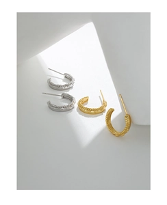 Macro detail of gold and silver S925 sterling silver C-shaped beaded textured earrings