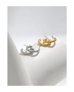 Macro shot of gold and silver S925 sterling silver C-shaped beaded texture hoop earrings