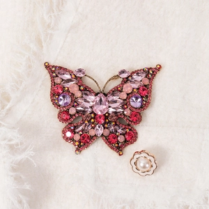 Elegant butterfly brooch with pink crystals and pearls on a premium knit background