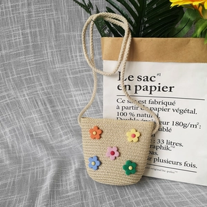 Close-up of beige straw woven toddler bag with colorful soft 3D flower decorations