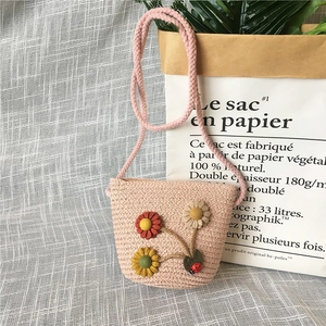 Detailed view of pink straw woven kids purse with 3D fabric flowers and ladybug charm