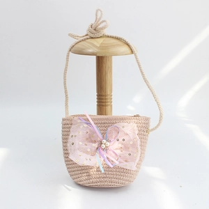 Macro detail of kids straw crossbody bag with large pink lace bow and pearl accents