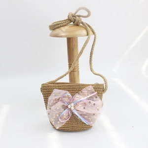 Detail of straw woven kids purse with pink sequin bow and pearl accents on wooden stand