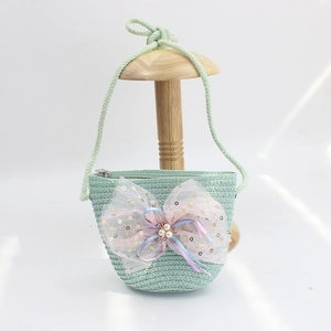 Detail of mint green woven straw crossbody bag for girls with a large pink mesh bow