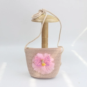 Detail of straw crossbody bag with pink tulle bow, sequins and cute doll figure