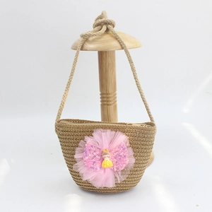 Detail of child straw bag featuring a large pink tulle flower and cute cartoon doll decoration
