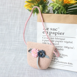 Detail of pink straw crossbody bag with floral accents and polka dot bow for girls