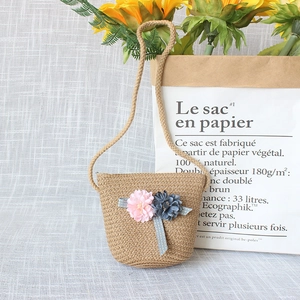 Detail of straw woven crossbody bag with silk flower accents and rustic hemp rope strap