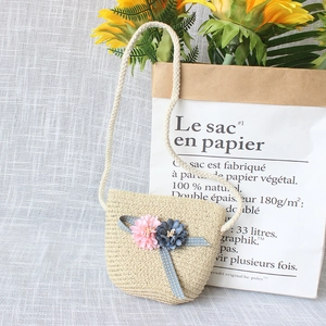 Detail of straw woven crossbody bag for girls featuring soft fabric flowers and ribbon