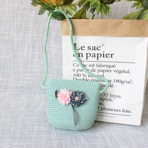 Detail of mint green woven crossbody straw bag with decorative flowers for kids