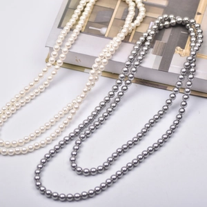 Detail view showing dual-layer white and grey faux shell pearl necklaces on a book
