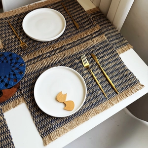 Detailed macro view of woven paper rope placemats with fringe edge in navy blue and natural tan