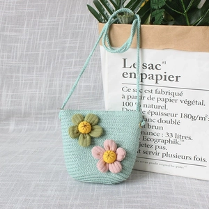 Détail d'un petit sac tricoté vert menthe avec fleurs en tissu et bandoulière en corde