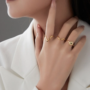 Three-piece stackable gold evil eye rings set worn by a model in white blazer