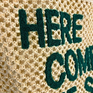 Straw shoulder bag with HERE COMES green embroidery and detailed woven texture