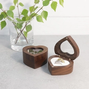 Detail view of heart-shaped walnut wood ring box with transparent window and white cushion