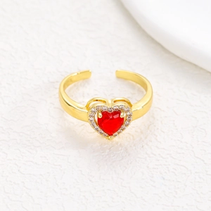 Macro view of adjustable gold heart ring featuring red gemstone and micro-pave zircons
