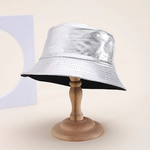 Detail of silver metallic PU leather bucket hat with fine horizontal texture on a wooden stand