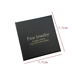Close-up of 7.7cm square black matte jewelry box featuring a gold foil designer logo