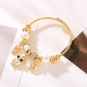 Golden beaded open bangle featuring owl and turtle charms with sparkling rhinestones