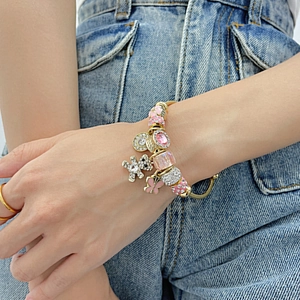Detail of a luxury gold beaded bracelet with pink charms and crystal bear on wrist