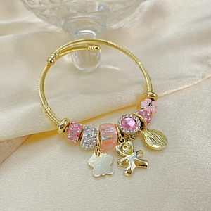 Detail of gold spiral wire bracelet with pink bear charm and crystal beads on satin